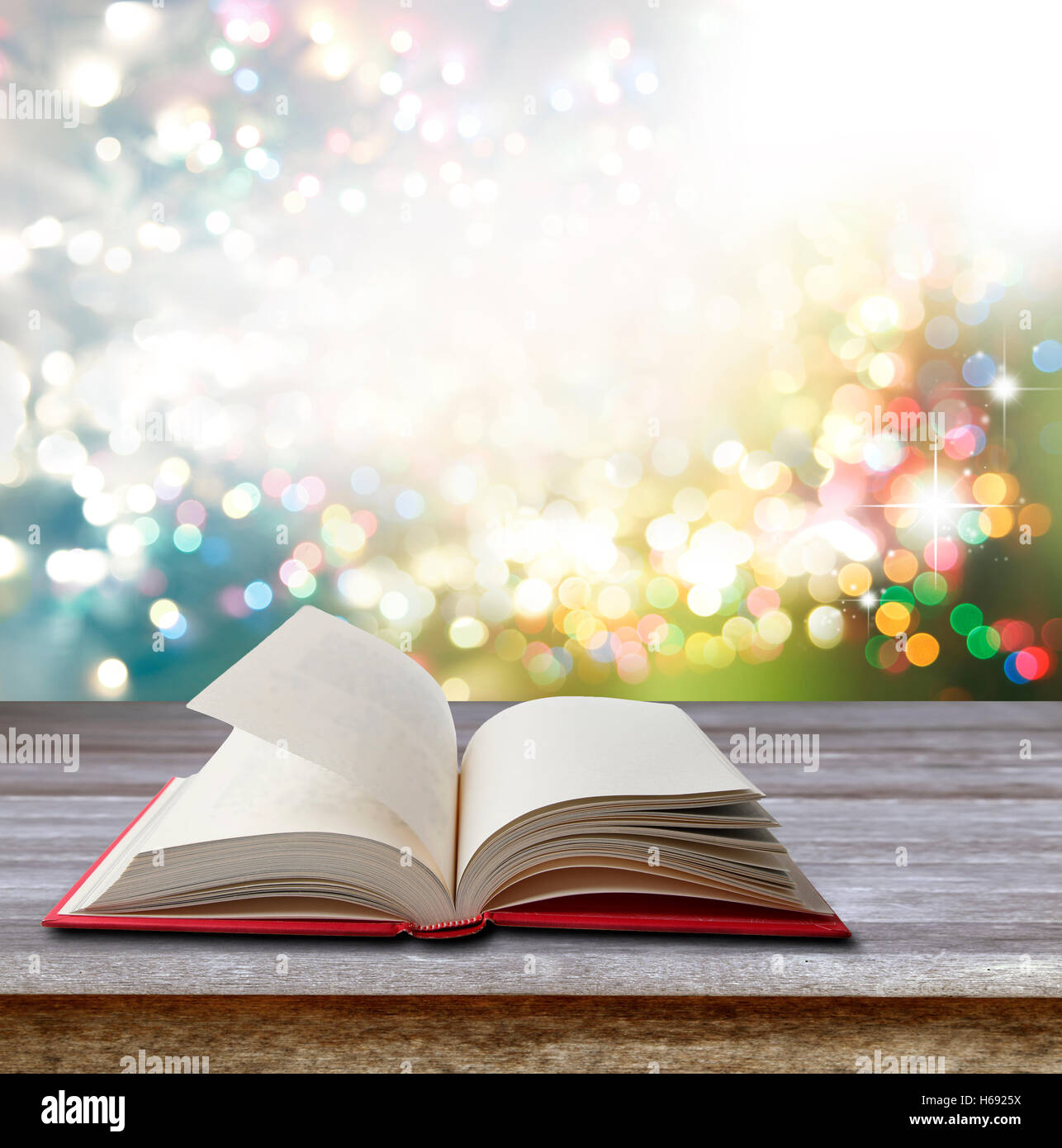 Open book on table in front of bright lights Stock Photo