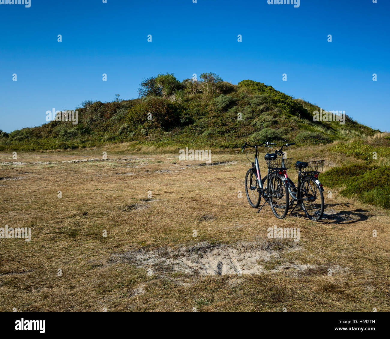 Melkhörndüne, Langeoog. Deutschland Germany.  A pair of traditional style hire bicycles parked at the base of the dunes.  It's a bright sunny day with clear blue skies. Stock Photo