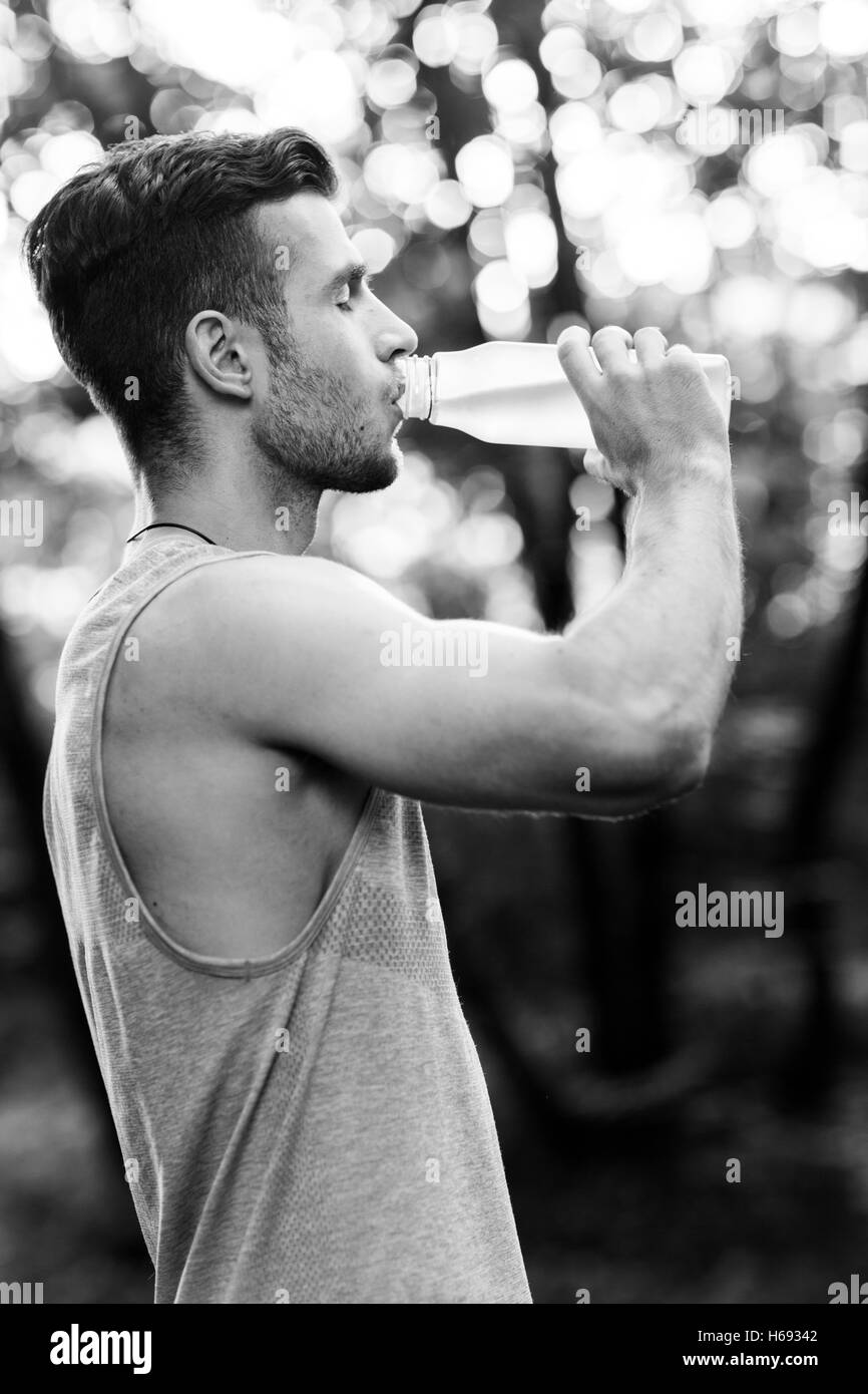 Young athlete drinking water in park.black and white photo Stock Photo