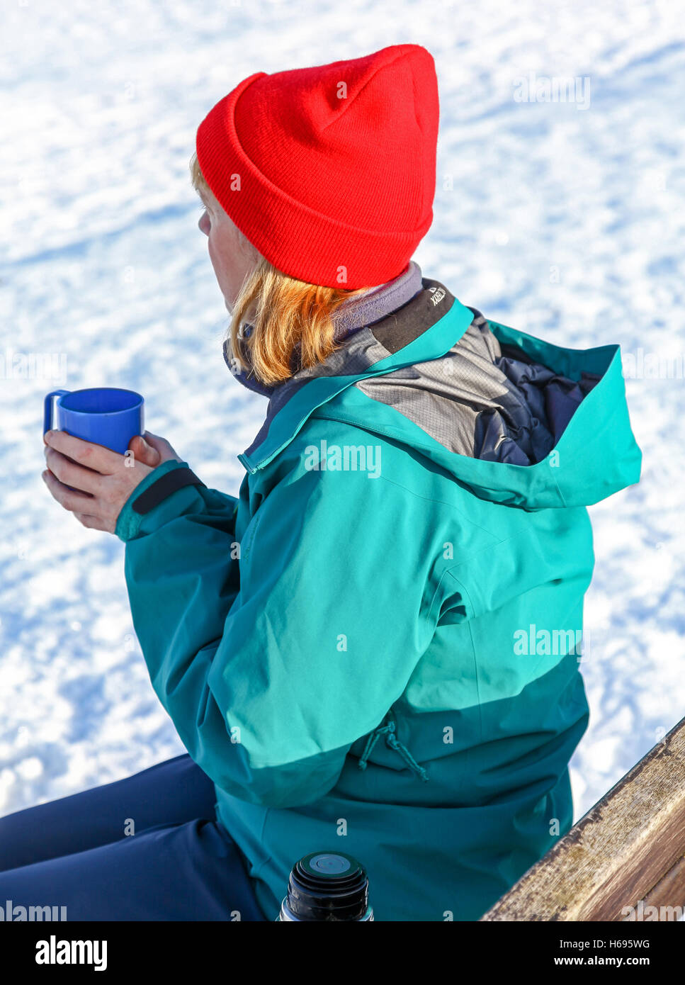 https://c8.alamy.com/comp/H695WG/a-woman-sitting-outside-in-the-snow-drinking-a-hot-drink-and-warming-H695WG.jpg