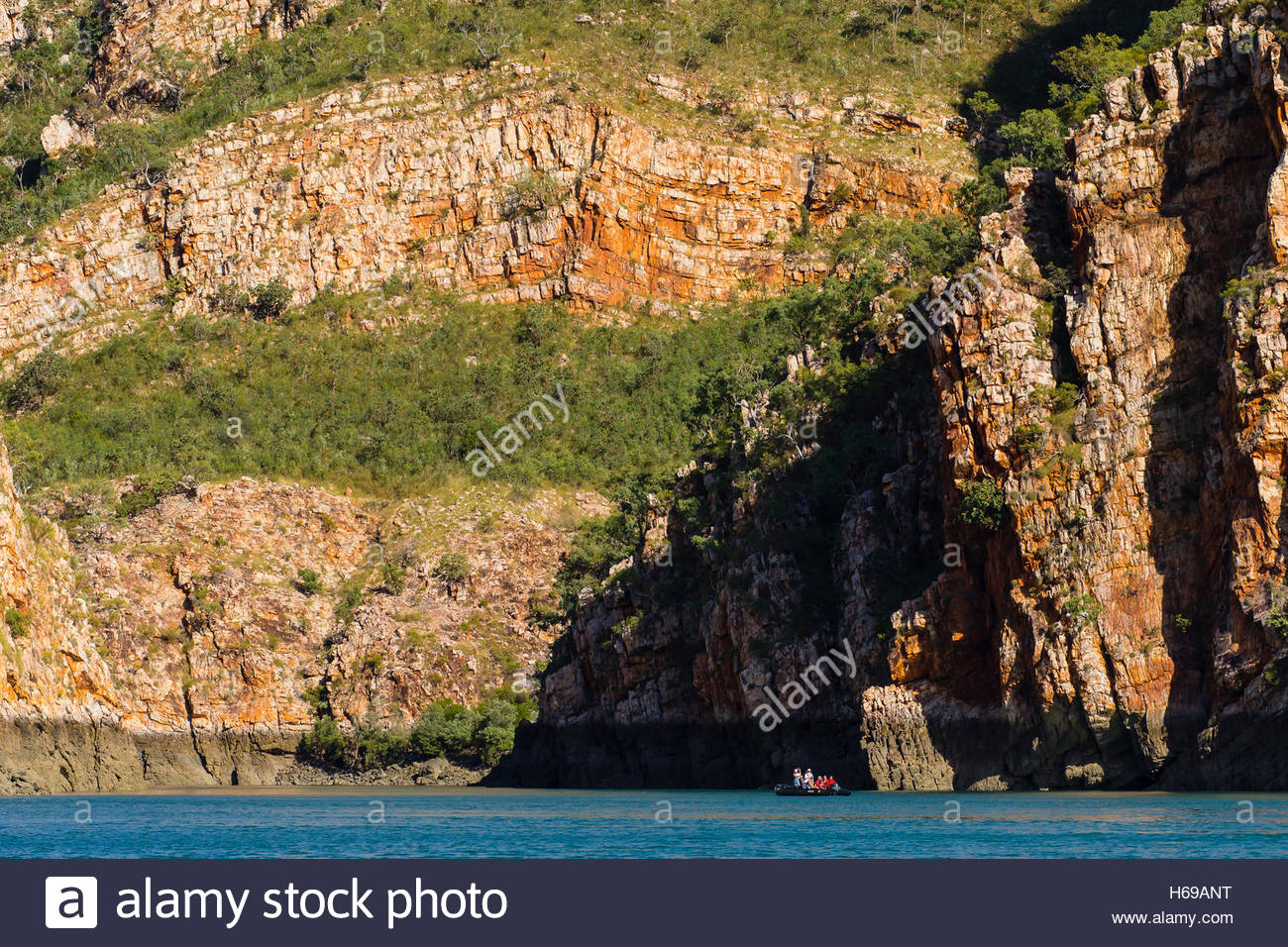 A small boat provides scale against a cliff in Cyclone Bay in the Kimberley Region of Northwest Australia. Stock Photo