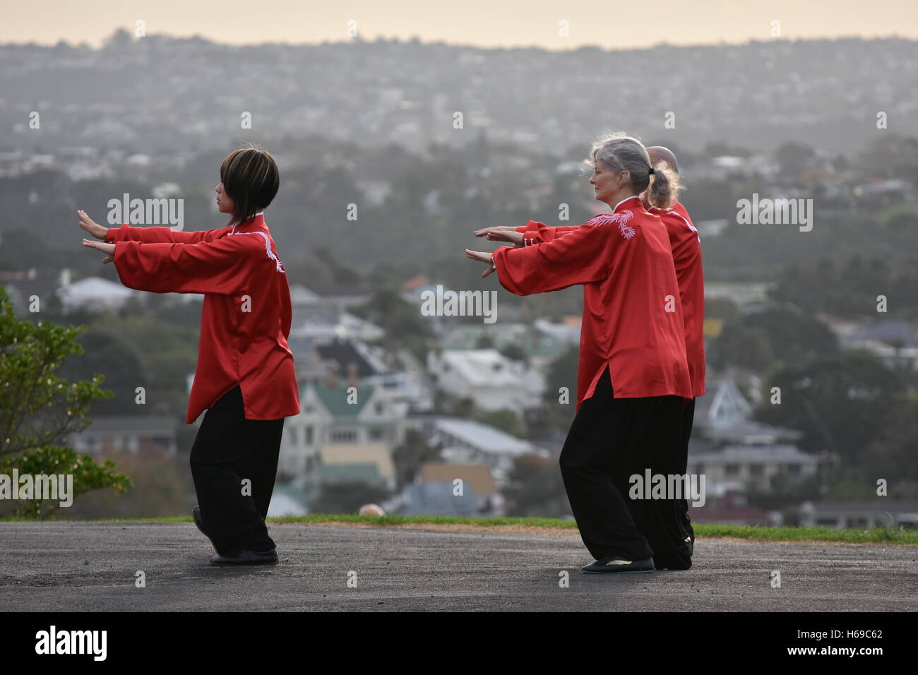 Three people performing Tai Chi form in traditional Chinese clothing Stock Photo