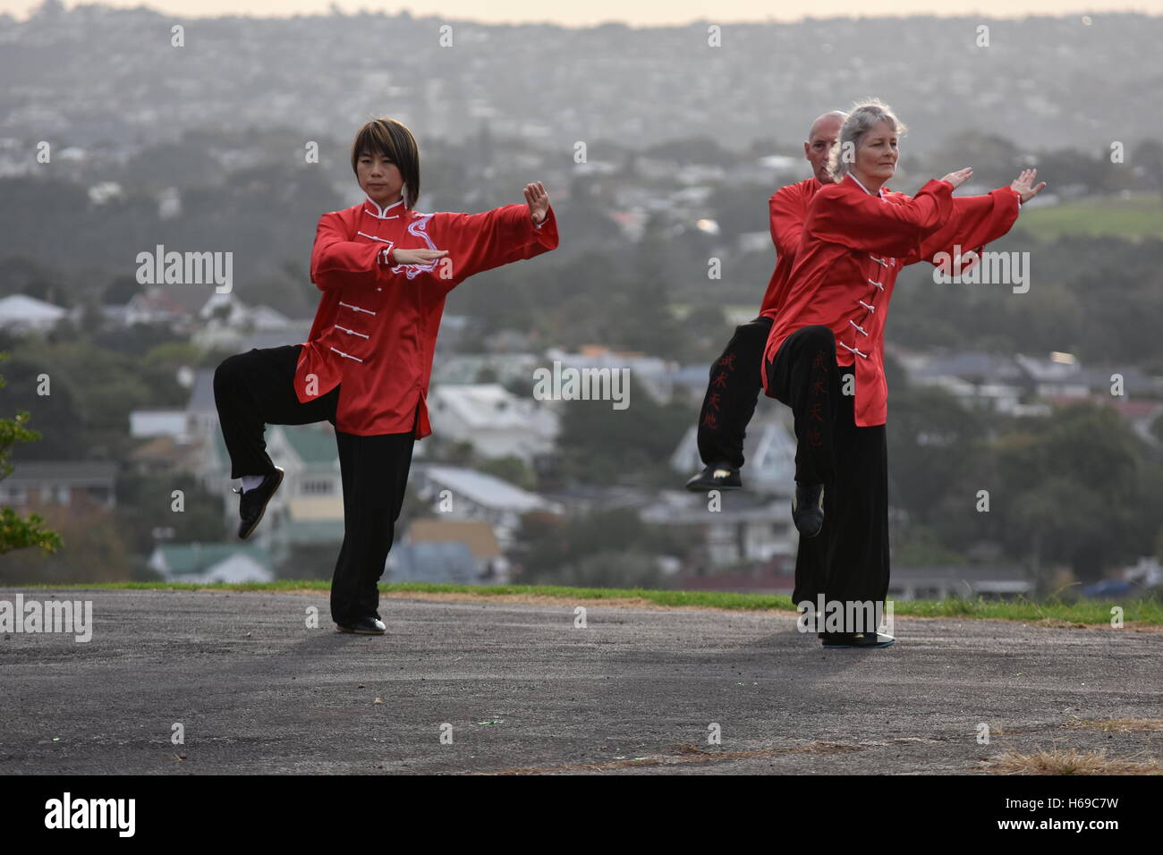 Three people performing Tai Chi form in traditional Chinese clothes Stock Photo