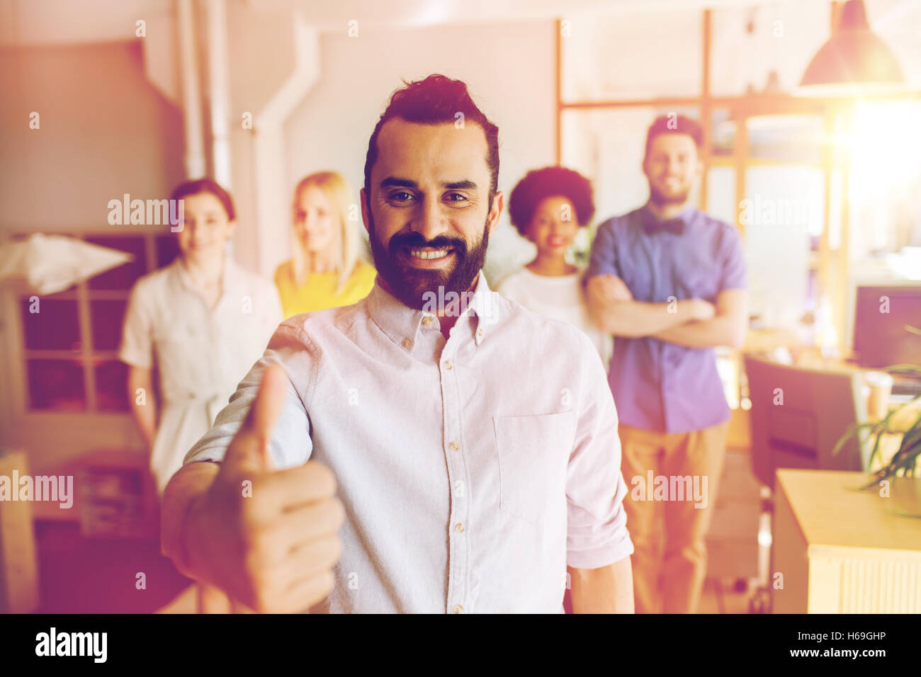 happy creative team showing thumbs up in office Stock Photo - Alamy