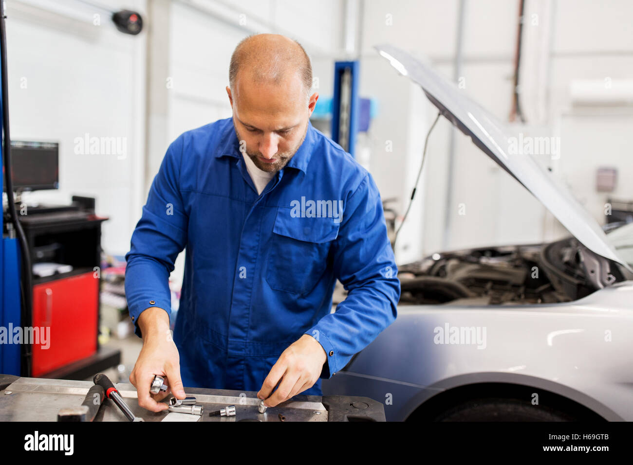 mechanic man with wrench repairing car at workshop Stock Photo - Alamy