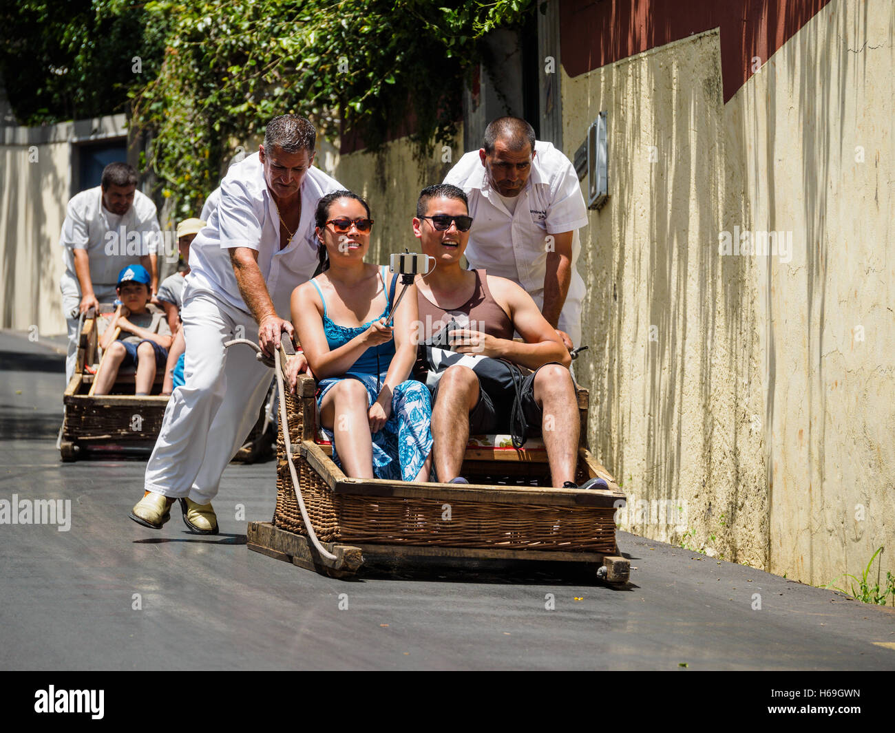 Toboggan drivers dressed in traditional white clothing carry tourists