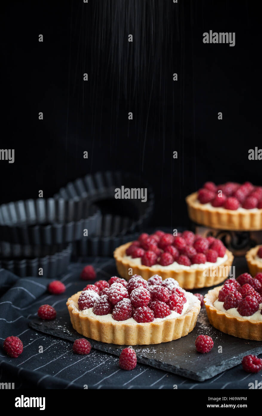 Delicious raspberry mini tarts (tartlets) with whipped cream on dark ...
