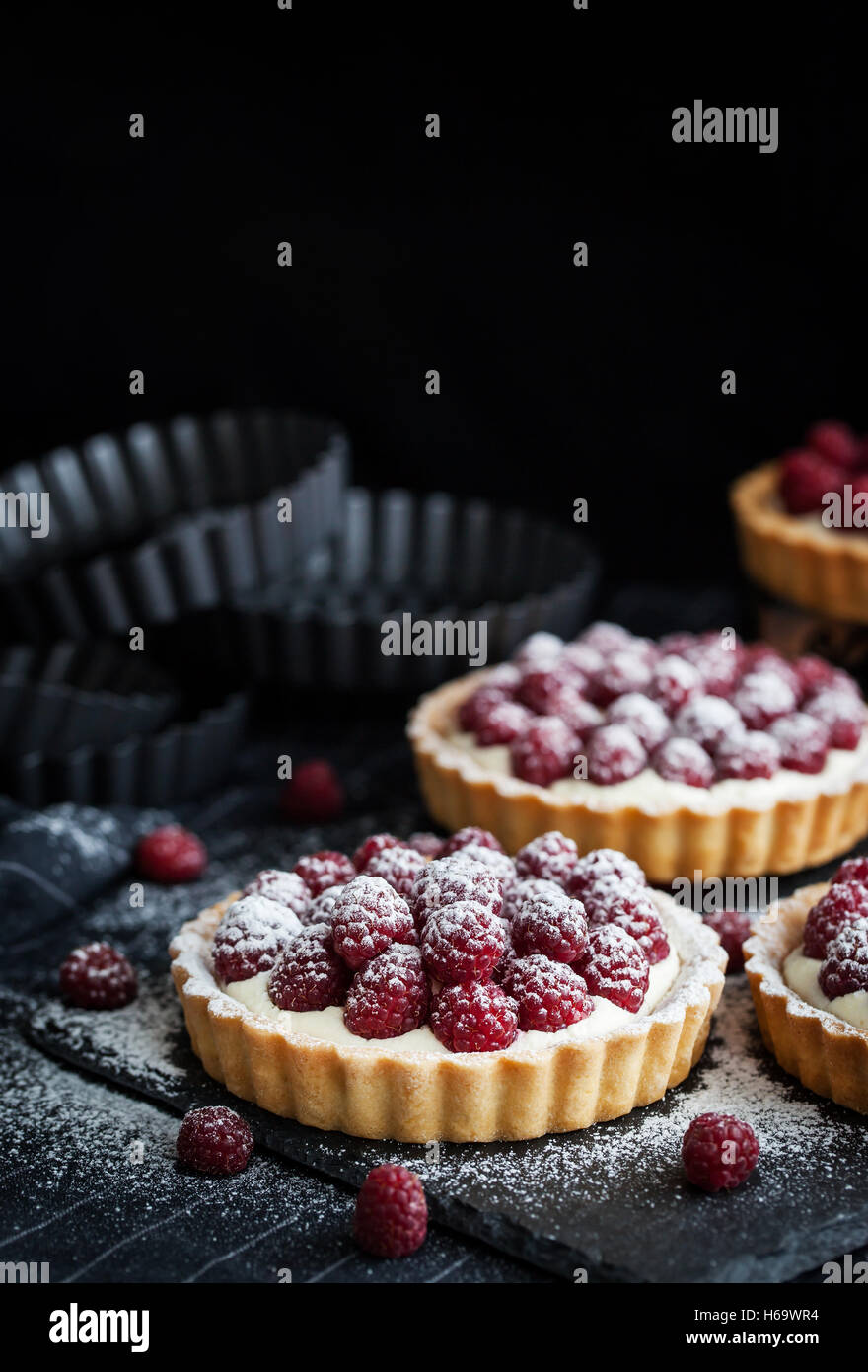 Delicious raspberry mini tarts (tartlets) with whipped cream on dark ...