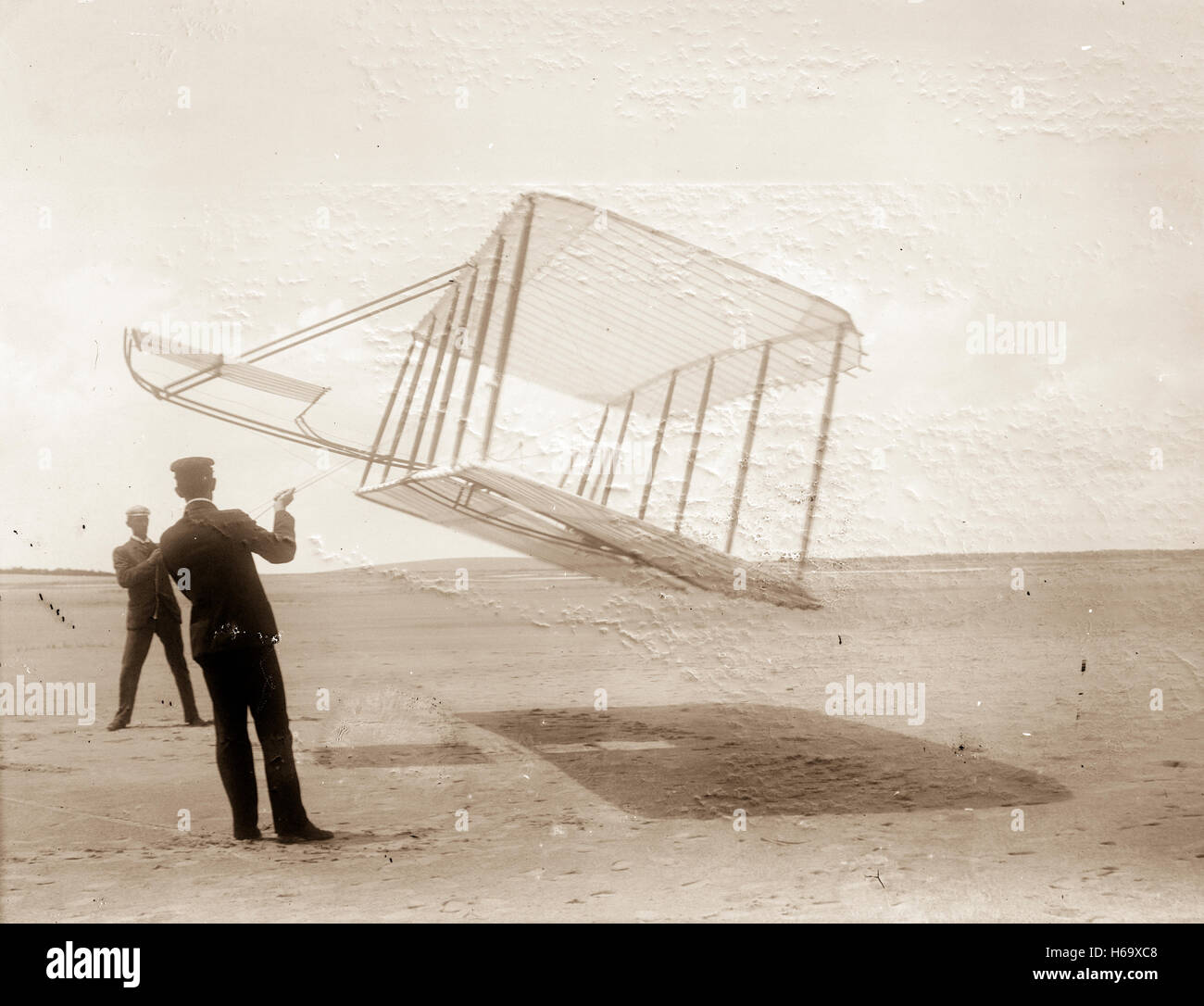 Side view of glider flying as a kite near the ground, Wilbur at left and Orville at right