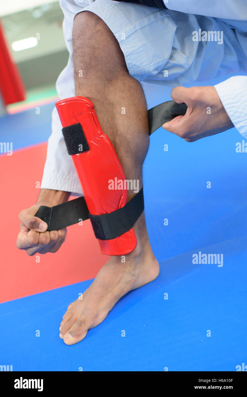 Martial artist attaching leg guard Stock Photo