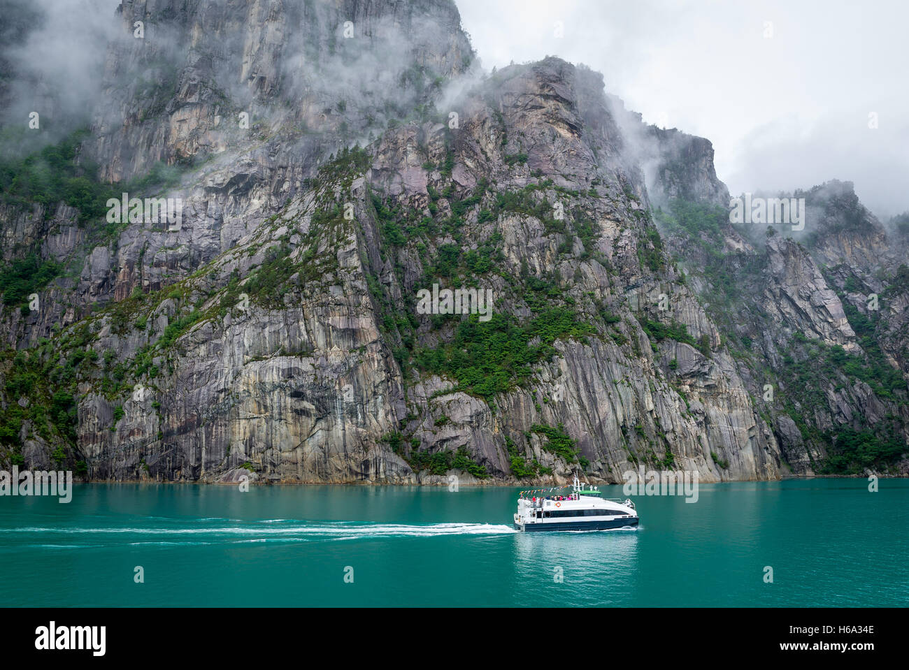 Small ferry at beautiful fjord with rocky shores and tourquise water. Stock Photo