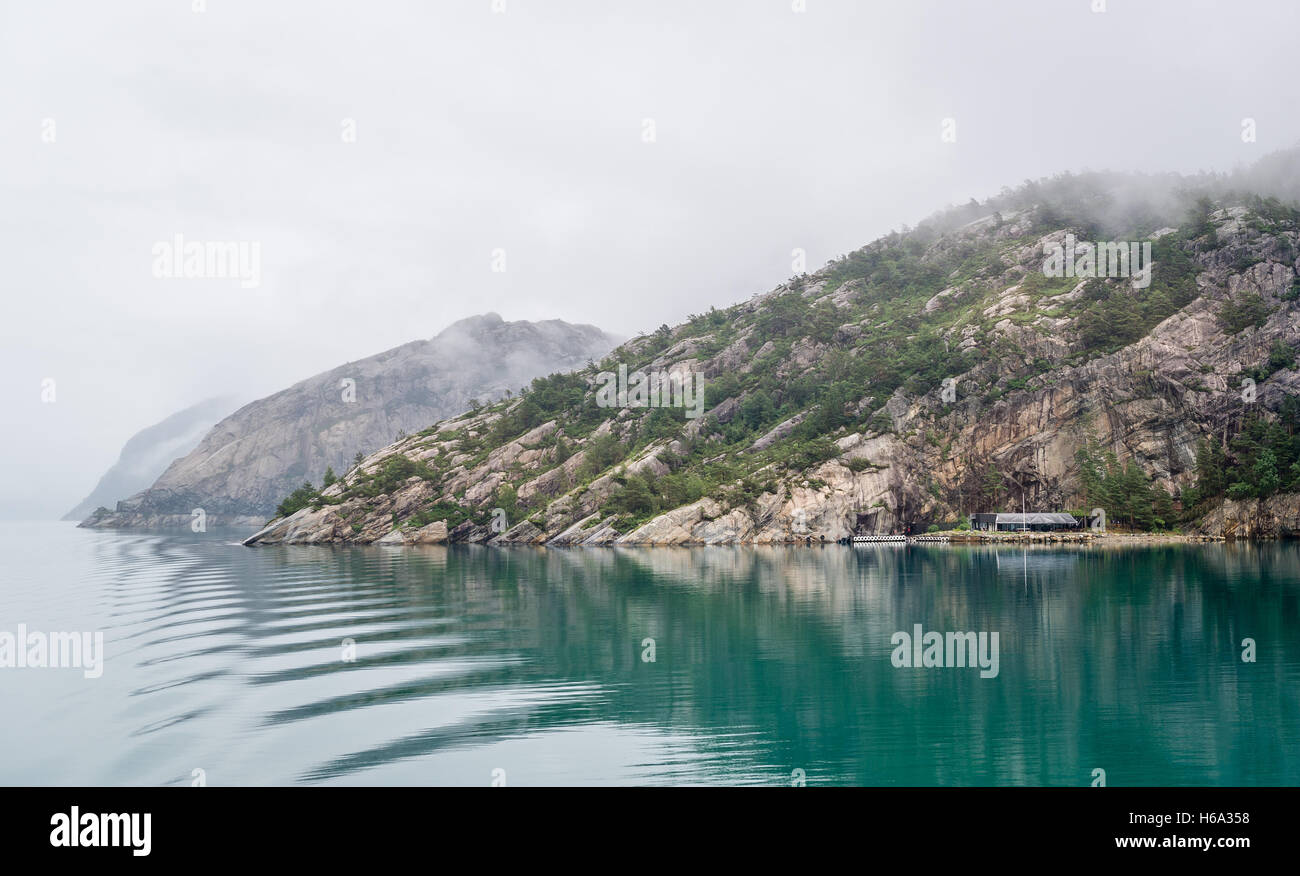 Norwegian fjord in fog and beautiful reflection on the water. Stock Photo