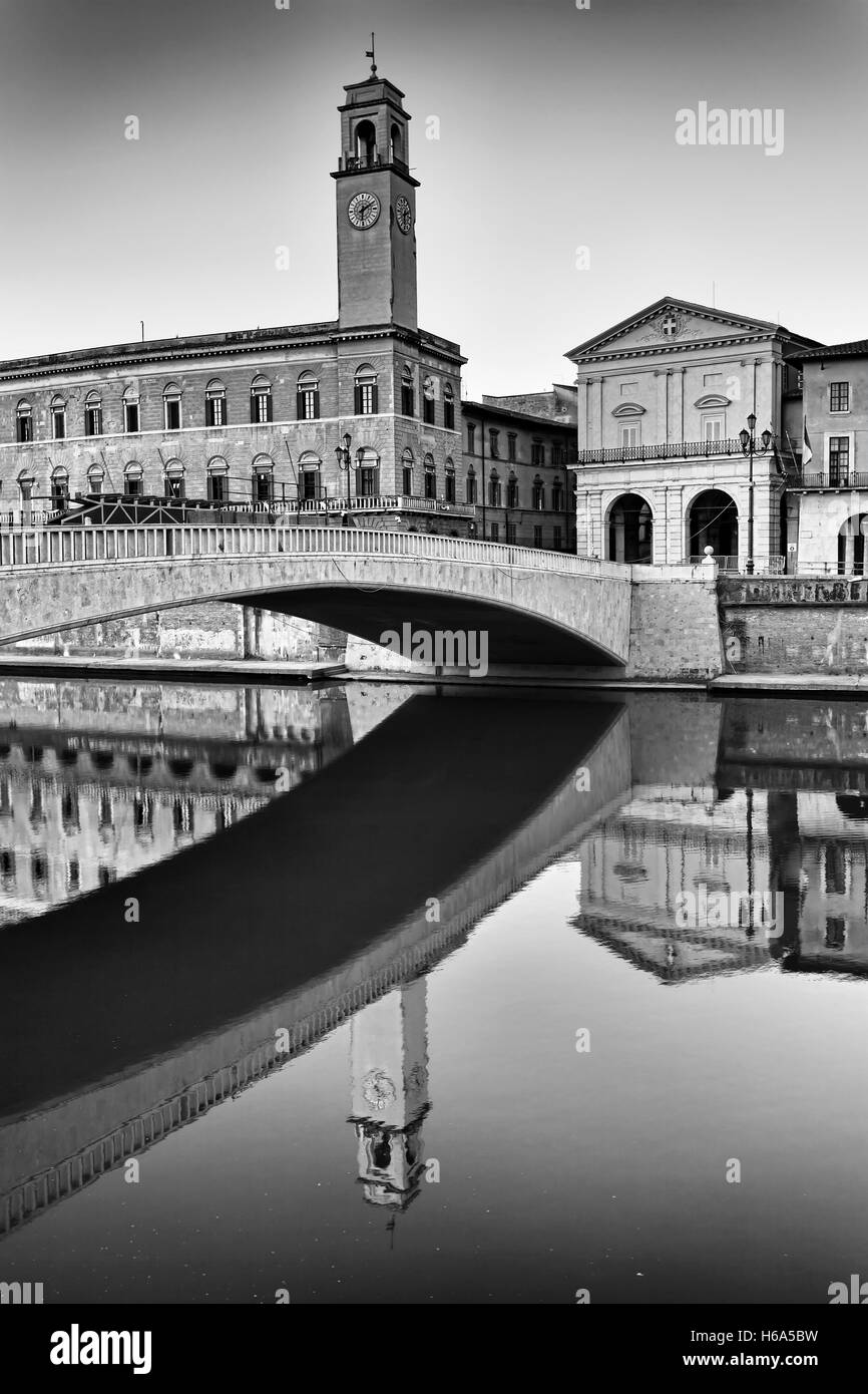 black-white fragment of Pisa city architecture along Arno river - historic riverfront, including arch of bridge, clock tower and Stock Photo