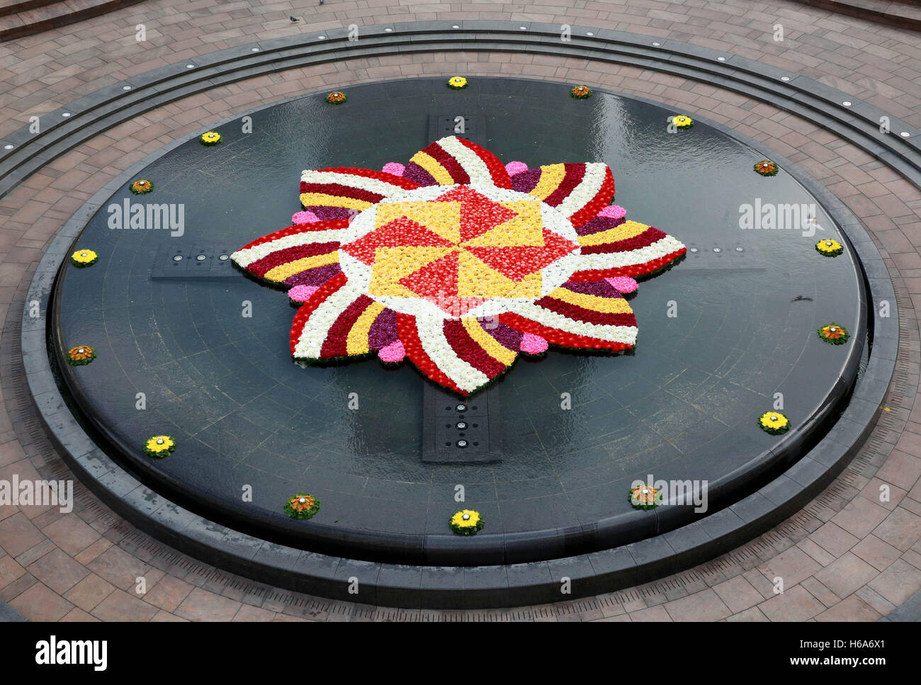 A 9x9m rangoli-style flower installation in the fountain at Cabot Square, Canary Wharf, London, made with over 6,000 flowers to celebrate Diwali, the Festival of Light. Stock Photo