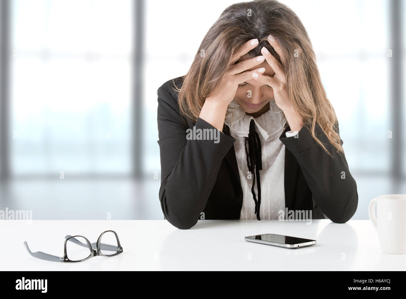 Businesswoman sitting at her desk depressed after receiving bad news, isolated in white Stock Photo