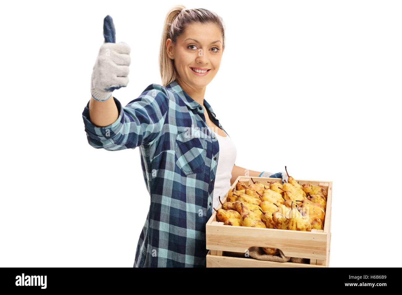 Happy female farmer giving a thumb up and holding a crate full of pears ...