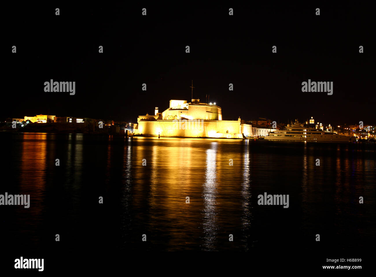 A well illuminated Fort at night stands guard across the Grand Harbour, Malta Stock Photo