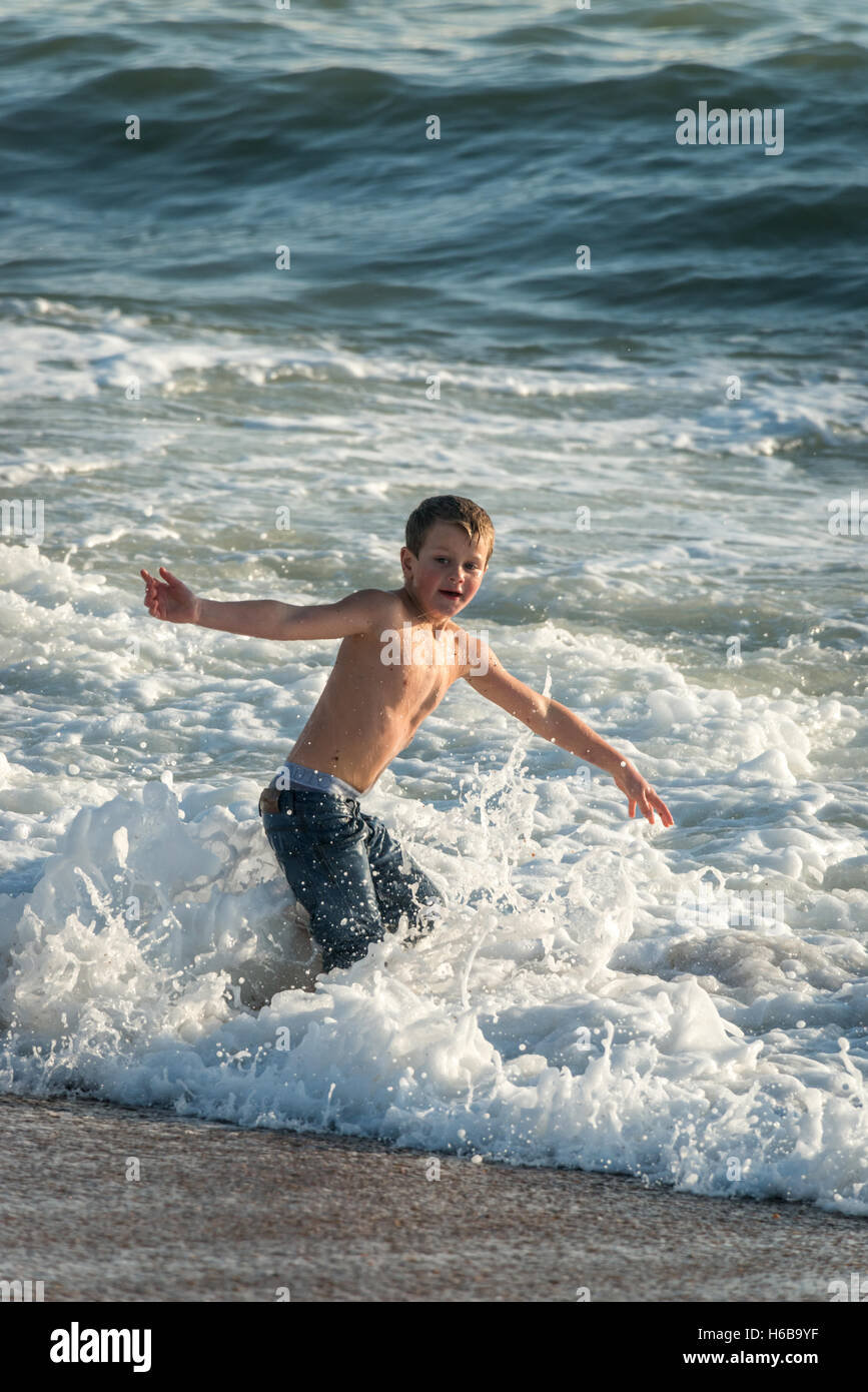 A young boy playing in the sea at the end of November Stock Photo - Alamy