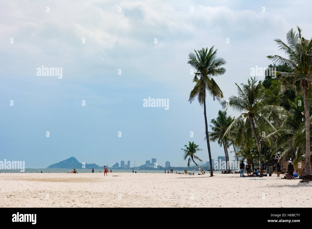 Hua Hin, Thailand - October 23, 2016: View at city beach at daytime with few tourists sunbathing and coconut trees Stock Photo