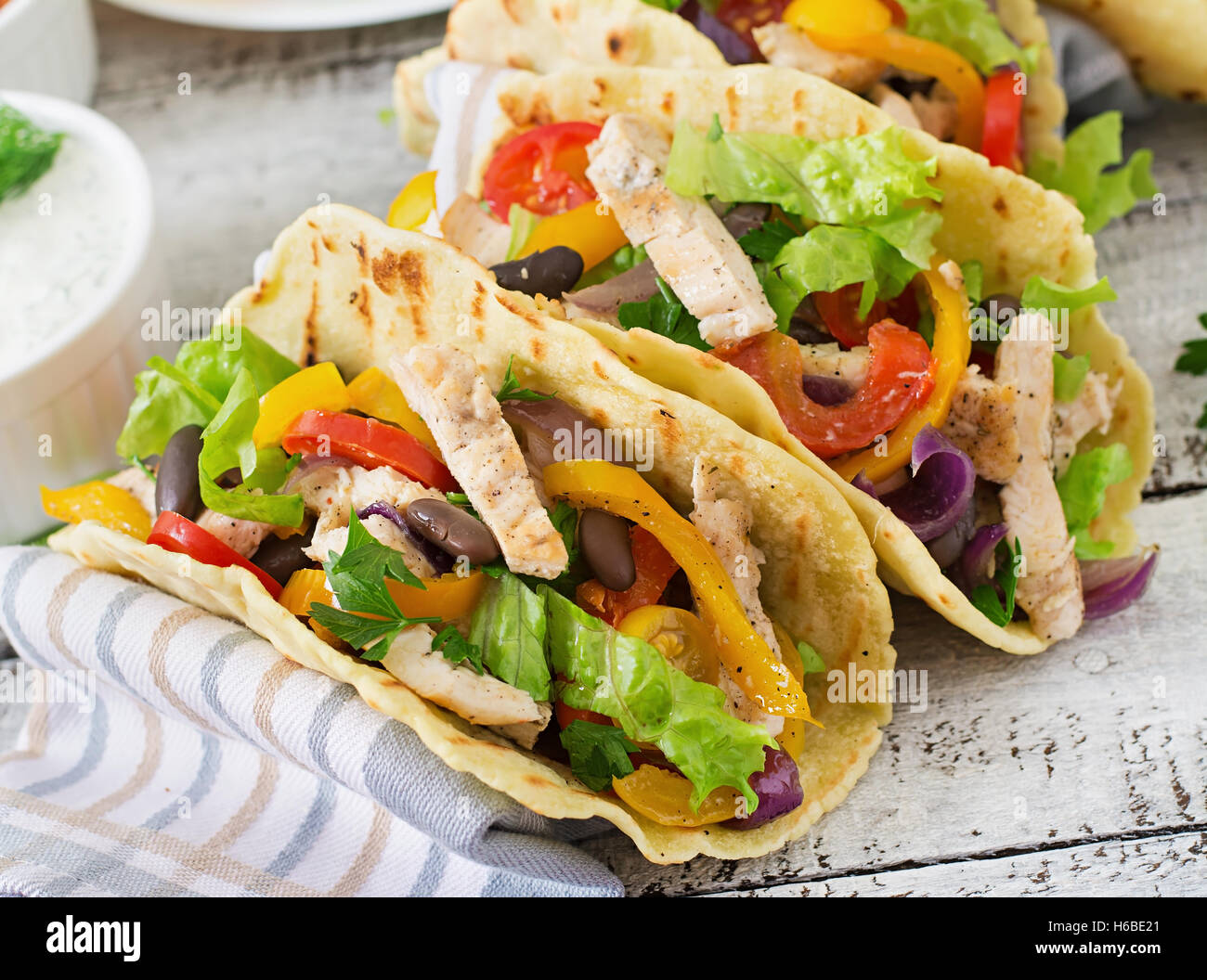 Mexican tacos with chicken, bell peppers, black beans and fresh vegetables and tartar sauce. Stock Photo