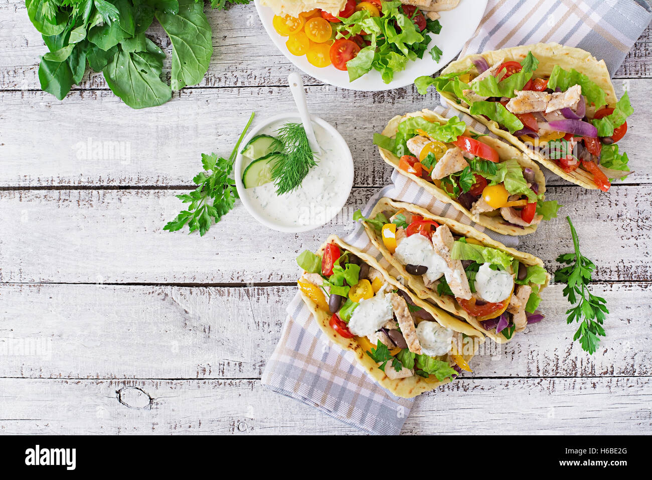 Mexican tacos with chicken, bell peppers, black beans and fresh vegetables and tartar sauce. Top view Stock Photo