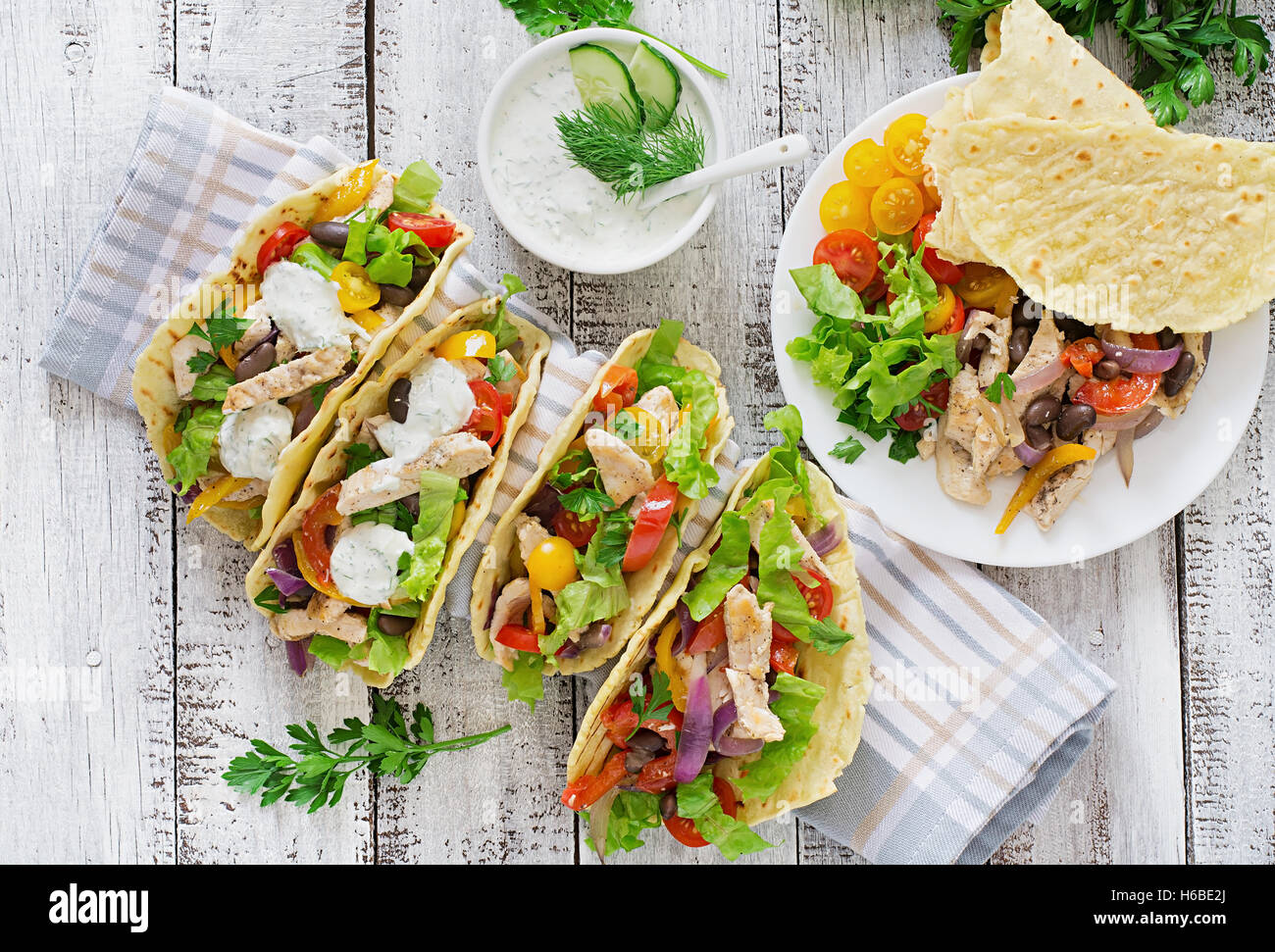 Mexican tacos with chicken, bell peppers, black beans and fresh vegetables and tartar sauce. Top view Stock Photo