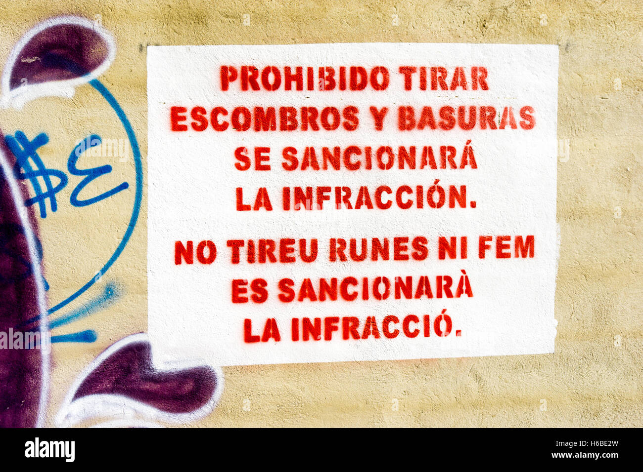A bi-lingual sign in Catalan and Spanish - 'It is prohibited to throw debris or rubbish offenses will be punished' Stock Photo