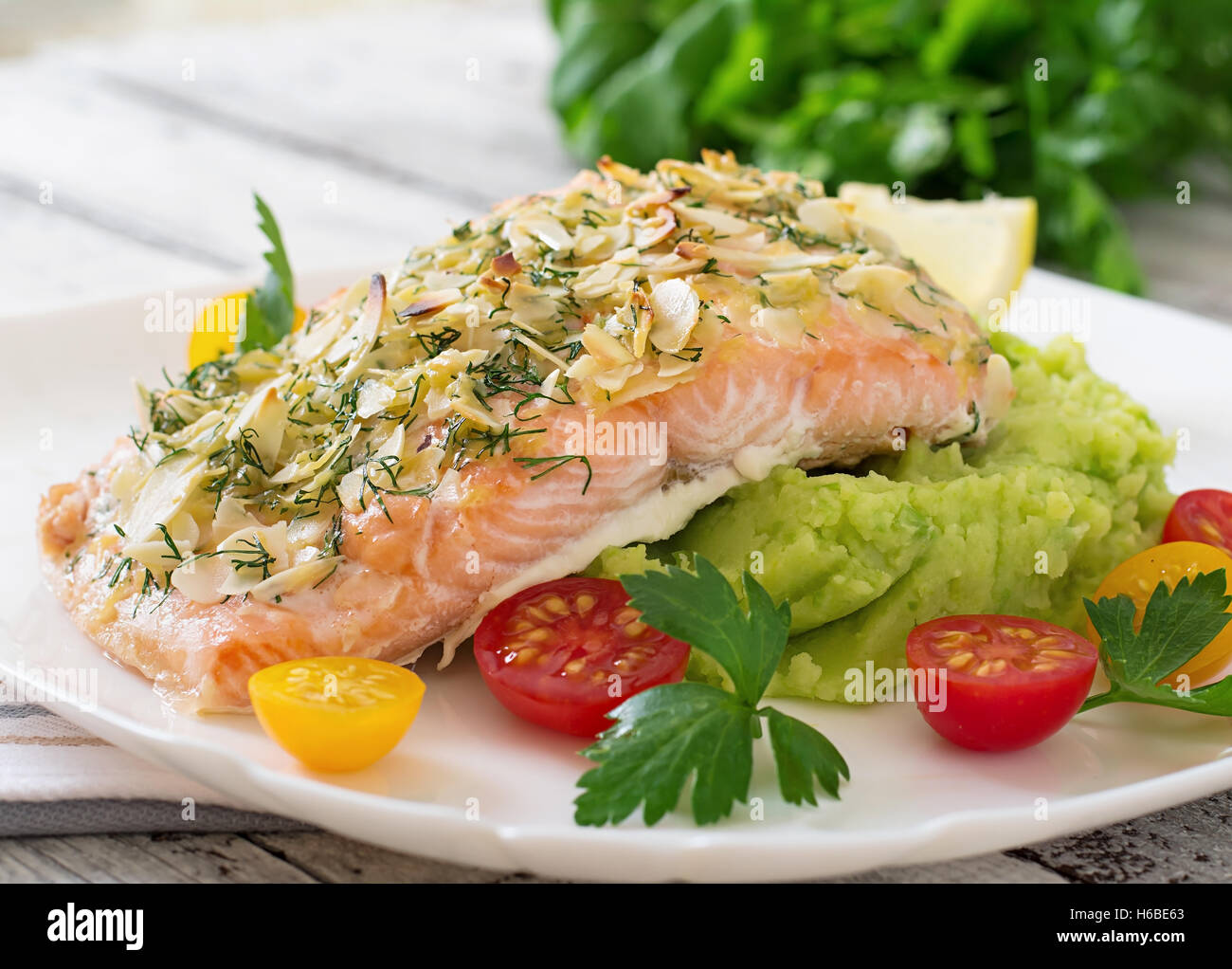 Baked salmon with cheese and almond crust and garnished with mashed potatoes and green peas Stock Photo