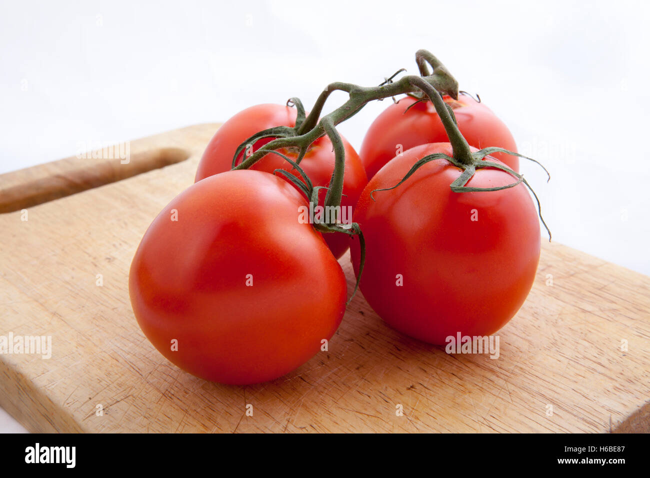 Tomatoes on a chopping board on the white background Stock Photo - Alamy