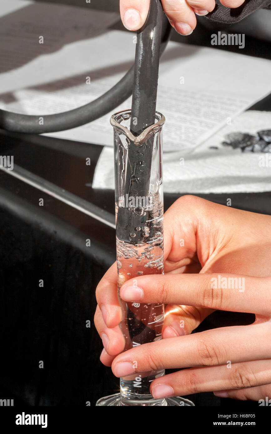 A graduated glass cylinder is filled with water in a high school chemistry laboratory. Stock Photo