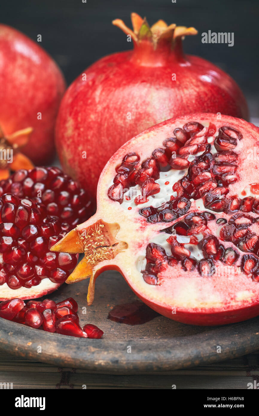 Ripe pomegranate fruit served on rustic plate Stock Photo