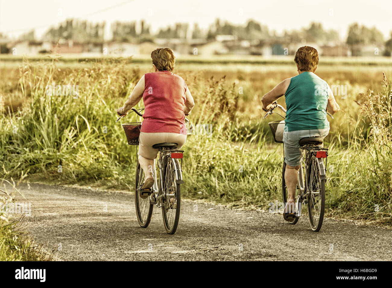 two middle-aged women going by bike through the countryside in Italy Stock Photo