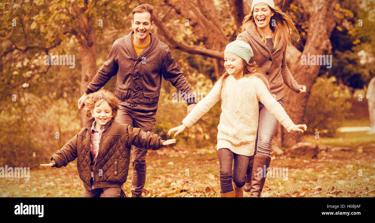 Smiling young family running into leaves Stock Photo