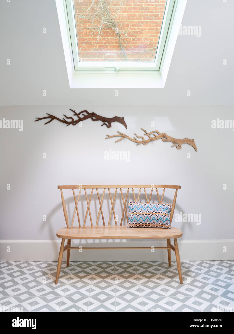 A Nordic style simple bench seat  in a small atrium lit by natural daylight from above via a Velux style Window, UK Stock Photo