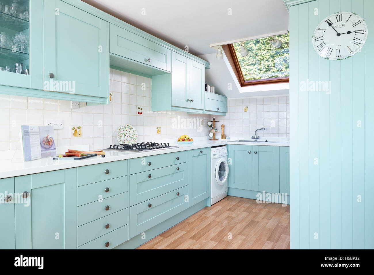 A contemporary, fresh kitchen incorporating an integrated oven, cooker, hood & work surfaces. Gloucestershire, UK Stock Photo