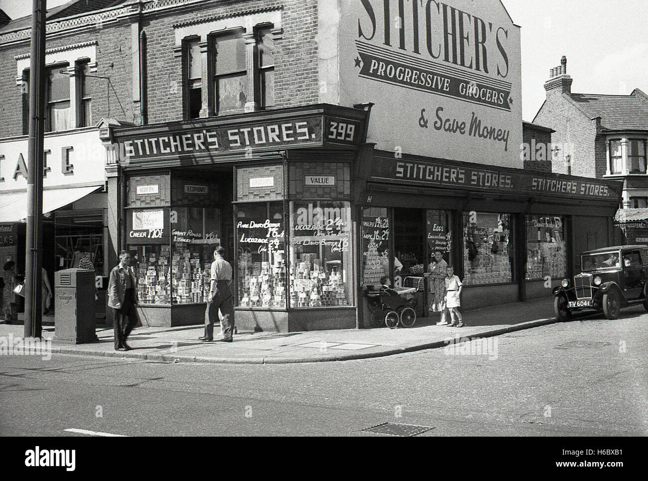 1930s, historical, England, exterior of a Stitcher's progressive grocery store, a small chain of such and a forerunner to the later supermarkets with their advertising slogan, 'Shop at Stitcher's & Save Money' and prices displayed in the windows. Stock Photo