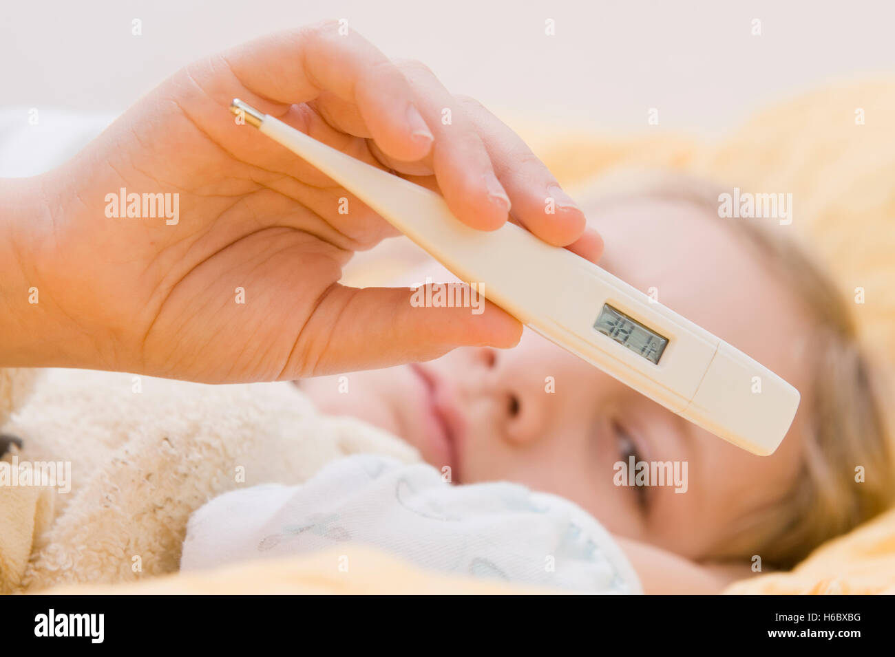 Sick girl with clinical thermometer in bed Stock Photo
