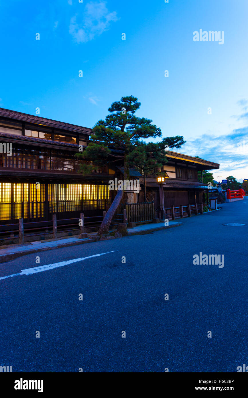 Front of traditional Japanese wooden house illuminated at twilight past Naka-bashi bridge in old town Takayama Stock Photo