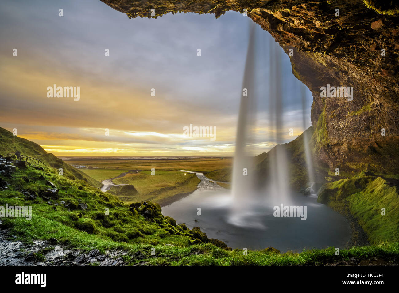 Summer sunset over the famous Seljalandsfoss Waterfall  in Iceland  viewed from behind the fall. Stock Photo