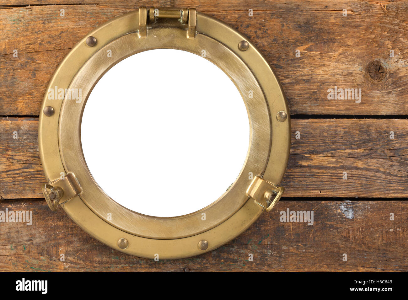 Vintage brass porthole in wooden wall, opening isolated with clipping path Stock Photo