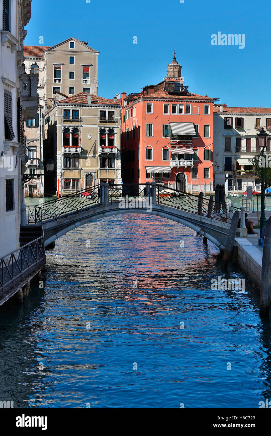 Colorful reflections in the water of a small canal leading off under a bridge from the Grand Canal - Venice in northern Italy. Stock Photo