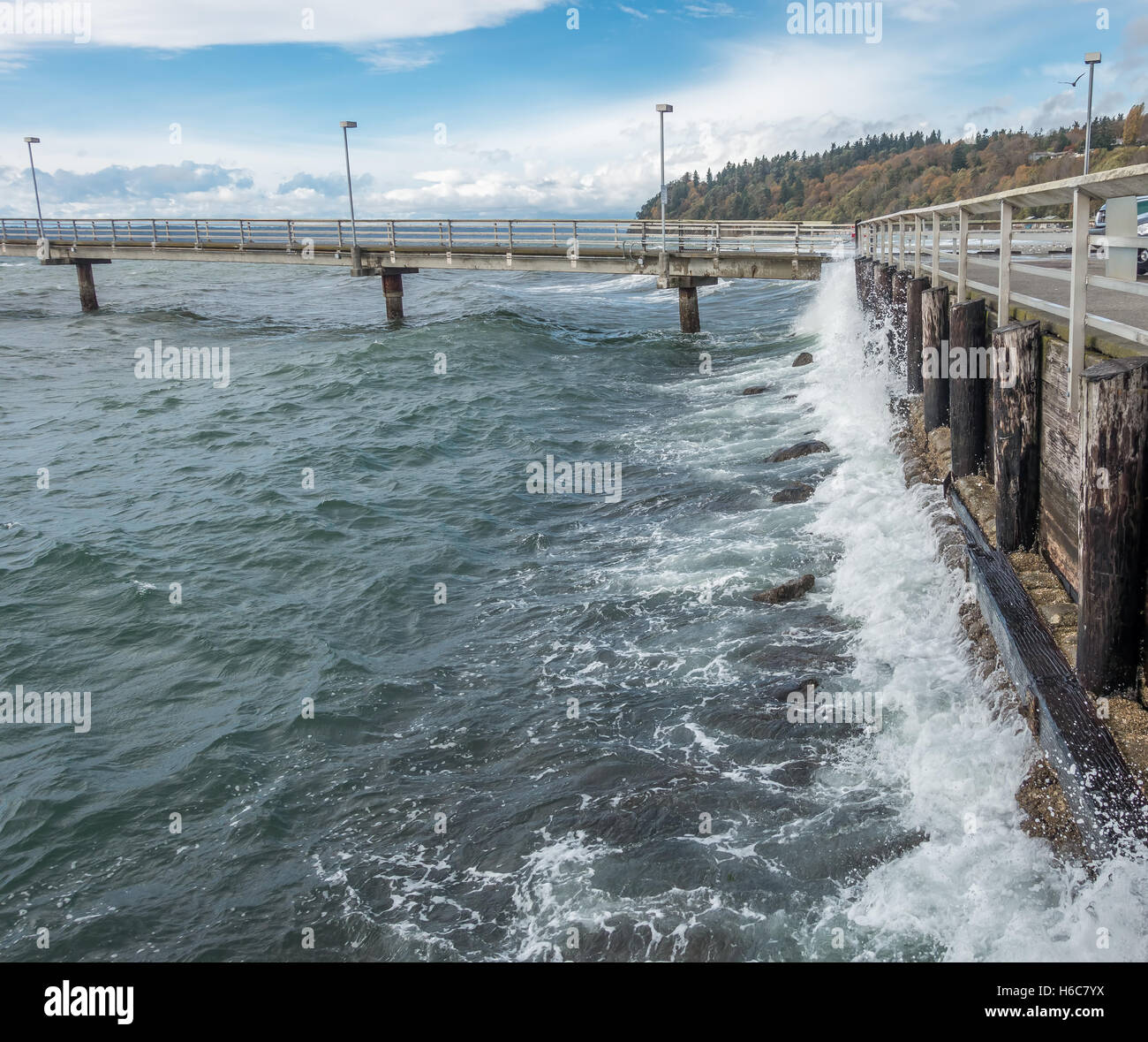 Surf crashes against a wood seawall resulting in whitewater explosions. Shot taken in Des Moines, Washington. Stock Photo