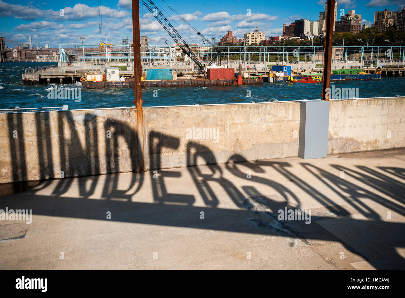 Projected shadow of the rotating 'Understanding' public art sculpture in Brooklyn Bridge Park in New York on Sunday, October 23, 2016. 'Understanding' by the artist Martin Creed features a 25 foot tall rotating red sculpture spelling out the word understanding reminiscent of a billboard on the side of a highway.  (© Richard B. Levine) Stock Photo