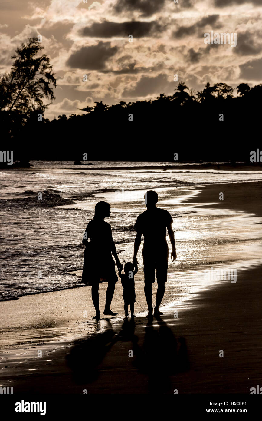 Silhouette of a family walking on the beach at sunset Stock Photo