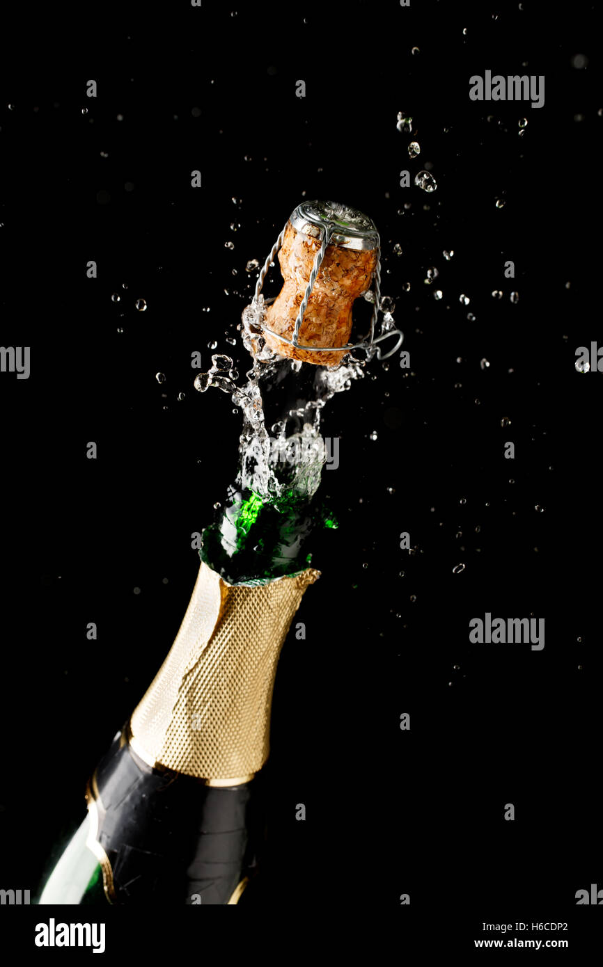 Bottle of champagne exploding isolated on black background Stock Photo