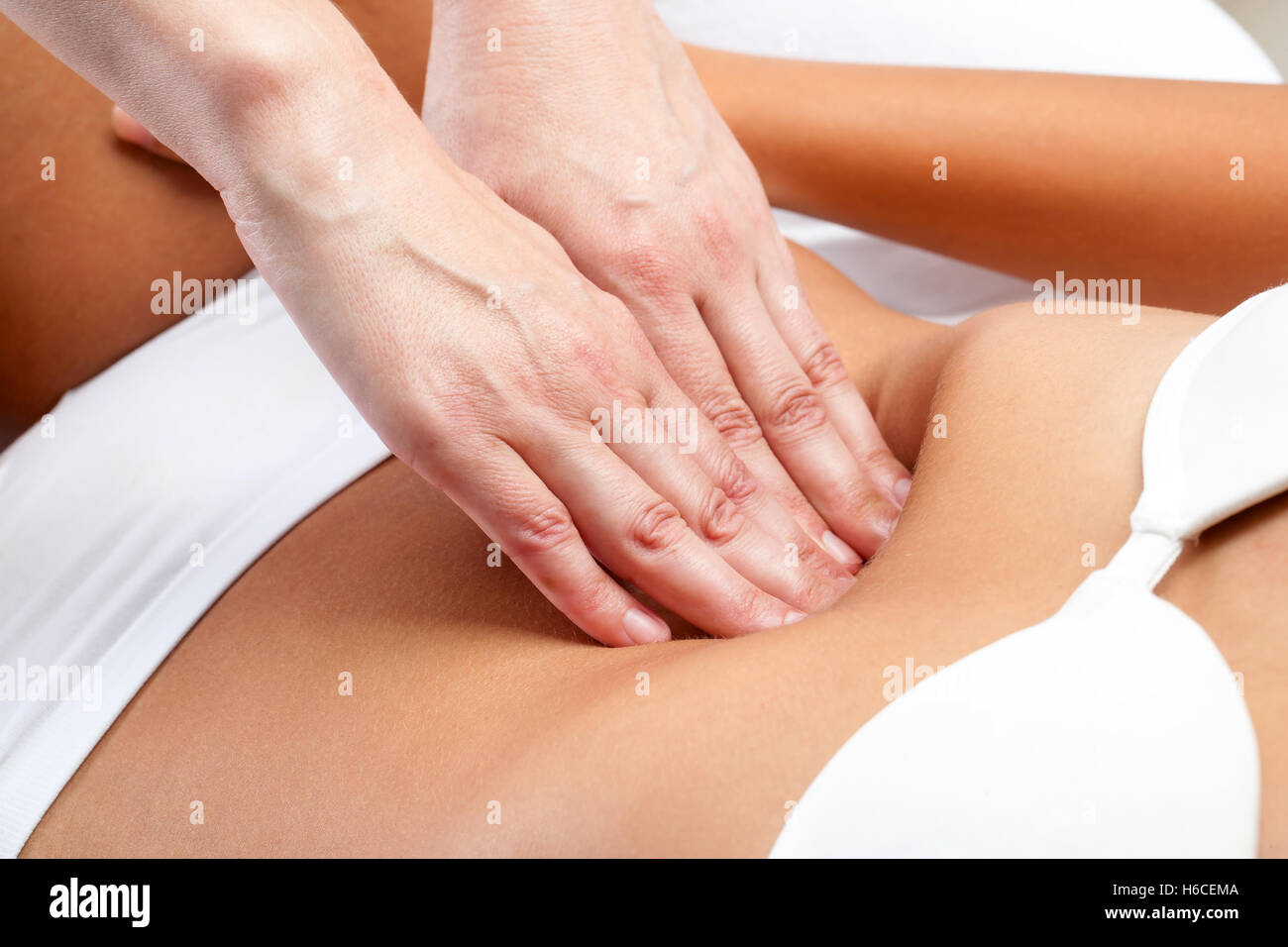 Macro close up of therapist hands doing visceral massage on female abdomen. Stock Photo