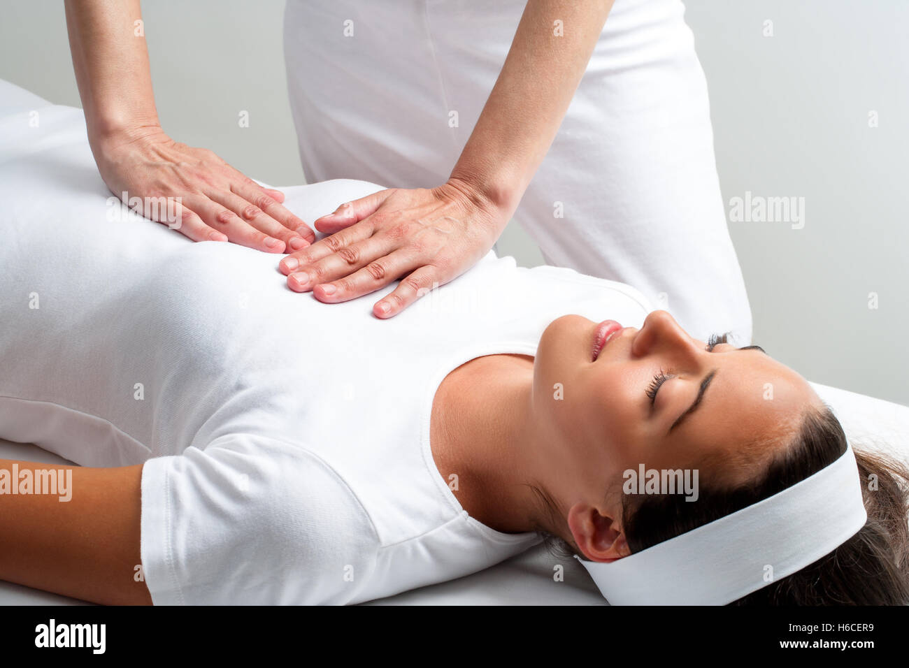 Close up of chiropractor pressing with hands on womans chest at reiki