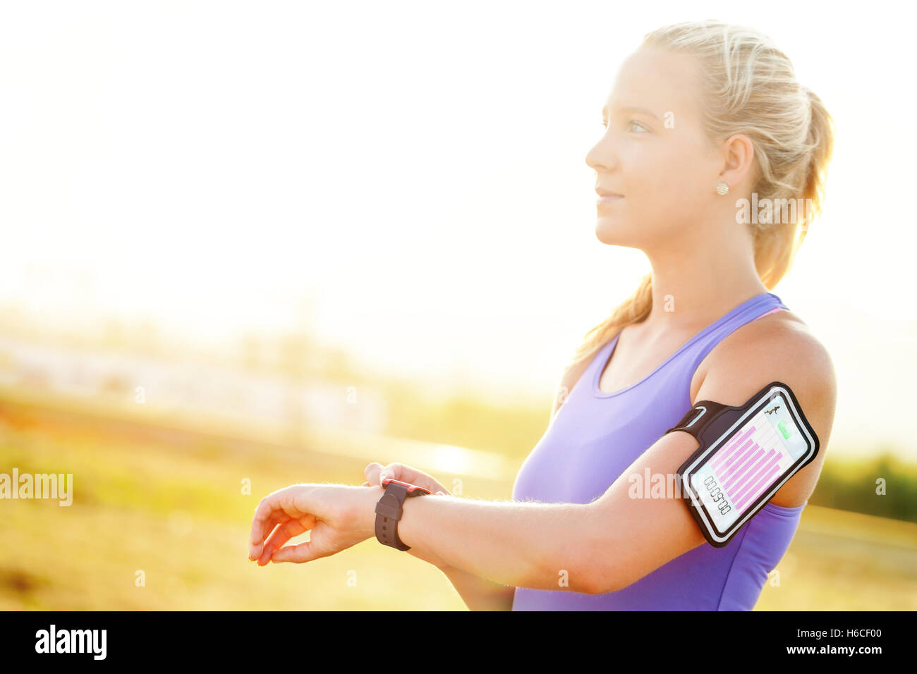 Close up portrait of attractive young woman setting workout on smart watch.Girl in sport wear with fitness chart. Stock Photo