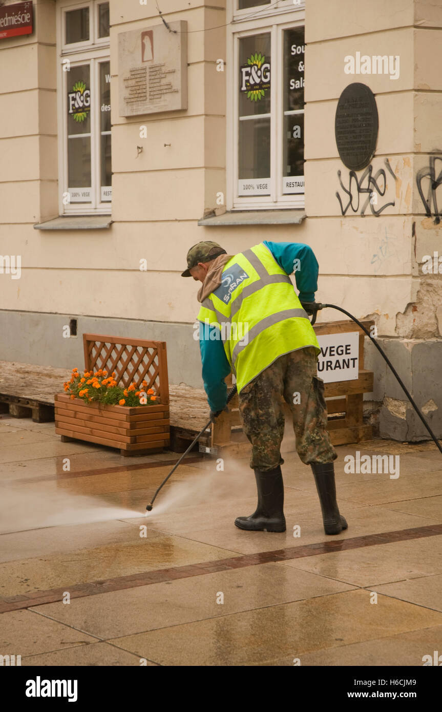 EUROPE, POLAND, Warsaw, Nowy Swiat, man cleaning the street with power