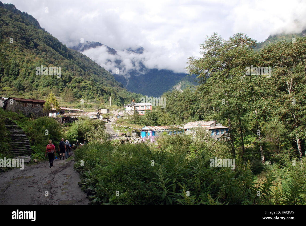 trekkers on the Annapurna circuit in Nepal walk towards a small village Stock Photo